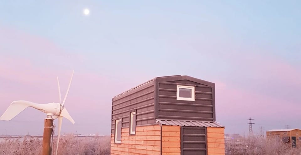 Tiny huis in de avondschemering met een kleine windmolen
